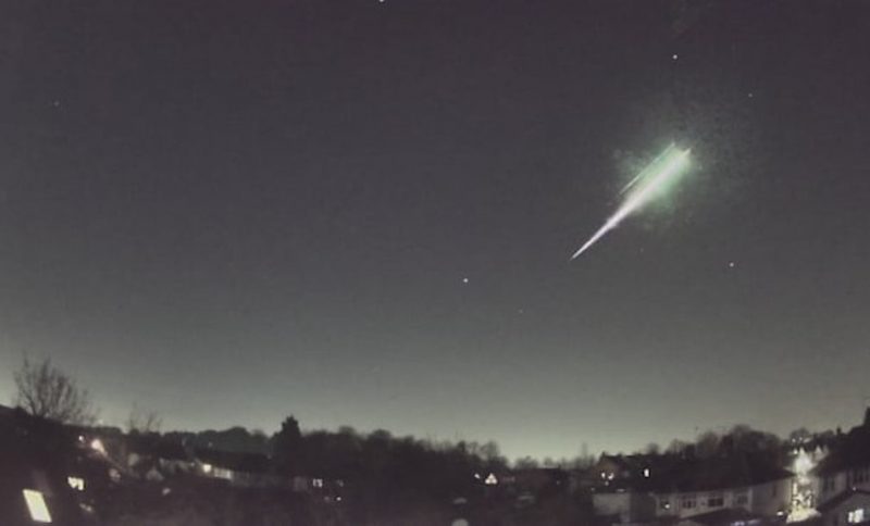 A streak of white, apparently exploding on the upper end, in a dark sky over trees.