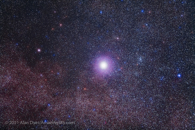 Star Alpha Centauri very bright against a backdrop of extremely dense field of fainter stars and dust clouds.