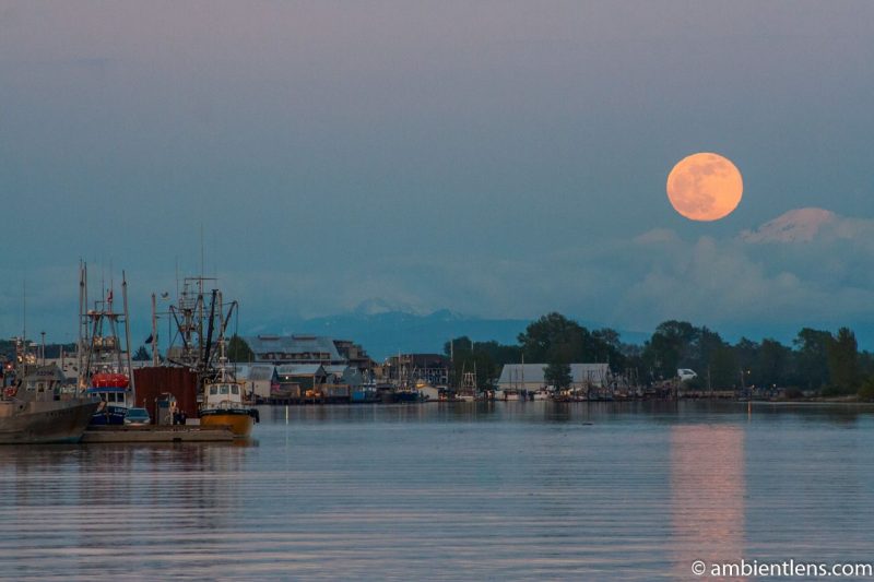 Harbor and mountains with full moon above.