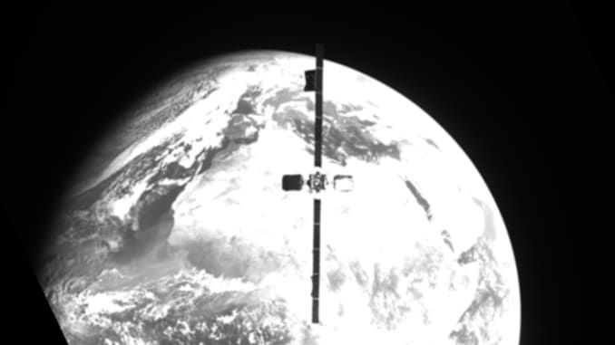 A satellite is pictured in grayscale, floating in space with Earth in the background.