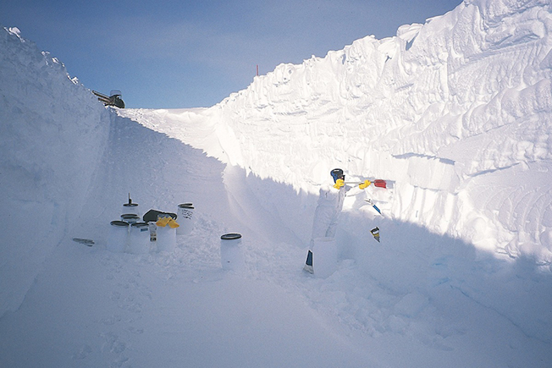 White cylinders with black tops standing in a large snow trench.