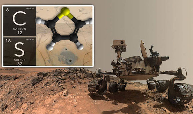 Robotic rover on brownish rocky terrain with inset image of a molecule.