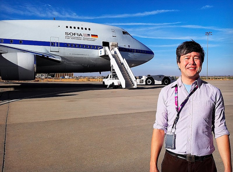 Man standing near jet plane on tarmac.