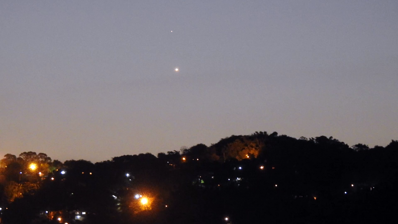 Mercury-Venus above a suburban skyline.