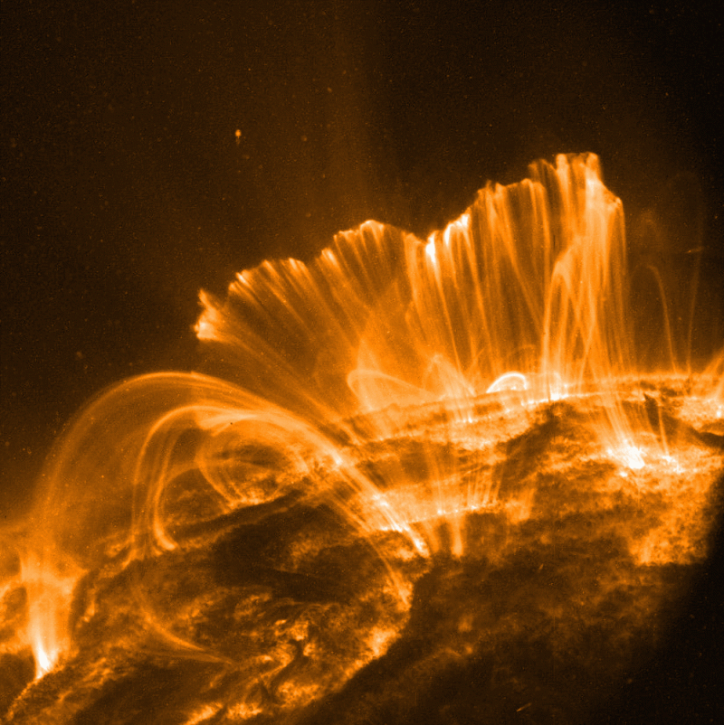 A photo of the surface of the sun with a towering explosion of plasma.