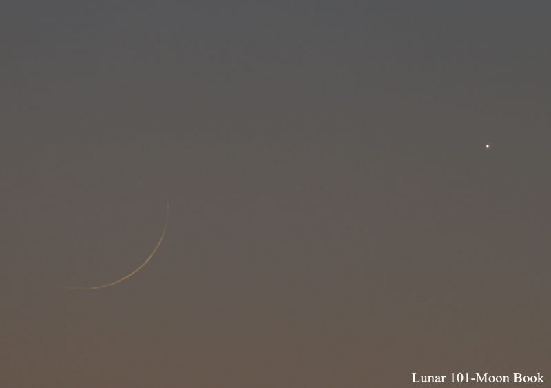 Very young and thin crescent moon, with bright planet Venus, in a twilight sky.