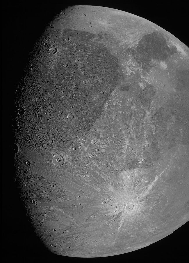 Moon-like body with craters, bright and dark patches, and lines.