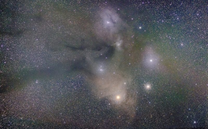 Speckles of white lights with brighter lights surrounded by colorful, wispy space clouds.