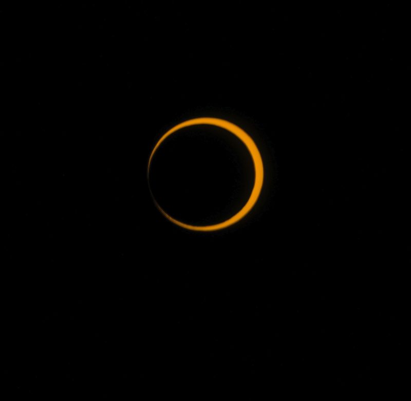 Black sky and nearly complete circle of orange with black center.