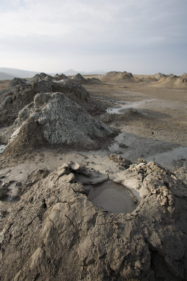Mud volcanoes: Cone with mud in a rocky landscape.