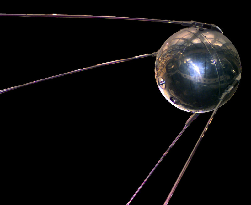Metallic ball with four long thin legs, in space.