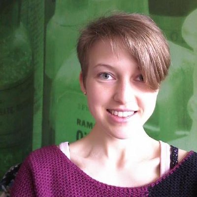 Smiling woman with short hair cut to hang down on one side of her face.