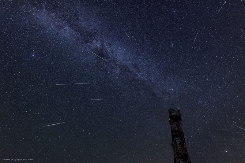 Panoramic view of the night sky with the Milky Way and multiple Perseid meteors.