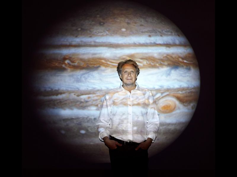 Man standing in front of projected image of Jupiter.