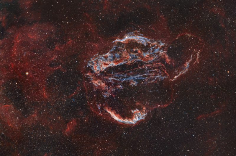 September deep sky: White and blue tendrils surrounded by reddish filaments and haze.