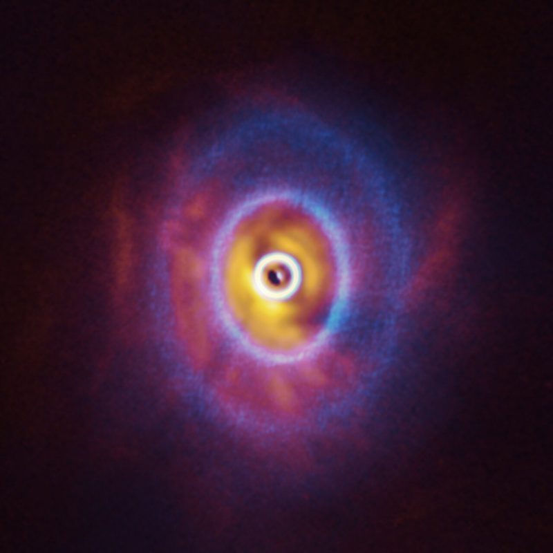 Circumtriple planet: Two fuzzy blue rings over red gaseous filaments with a white-ringed dark spot in the center.
