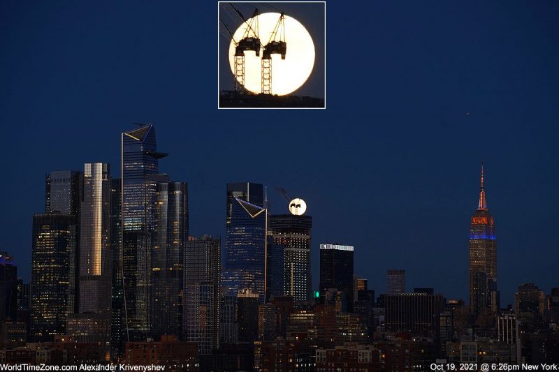 Full moon rising in the early evening with the skyline of New York City in the foreground.