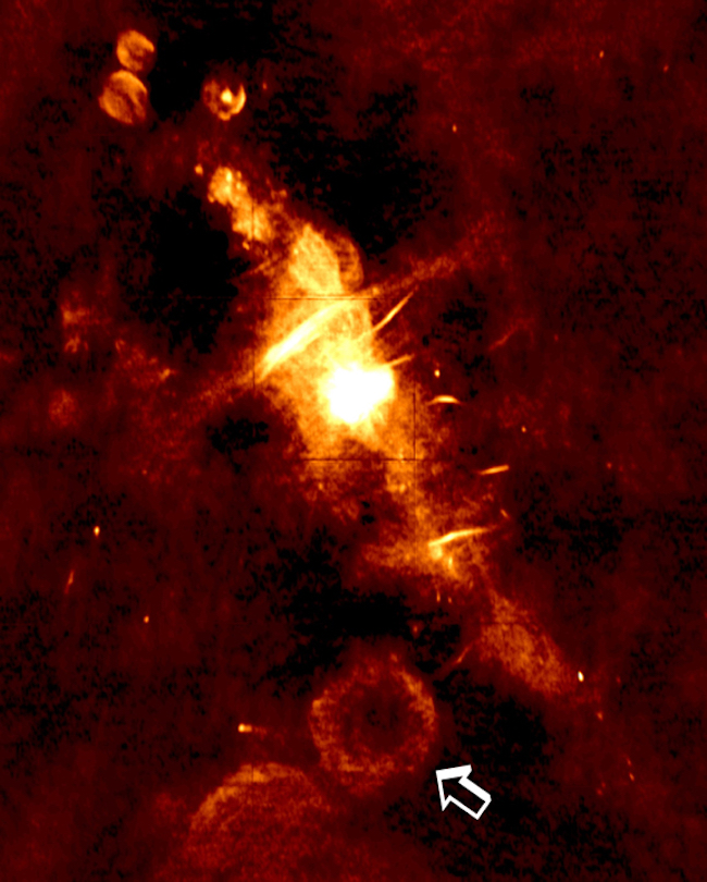 Bright white spot surrounded by dimmer glowing cloud-like features, with arrow pointing to one.
