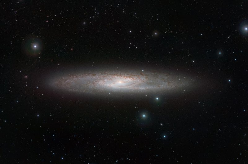 Spiral galaxy seen at an angle, white steering wheel shape in the middle, in constellation Sculptor.