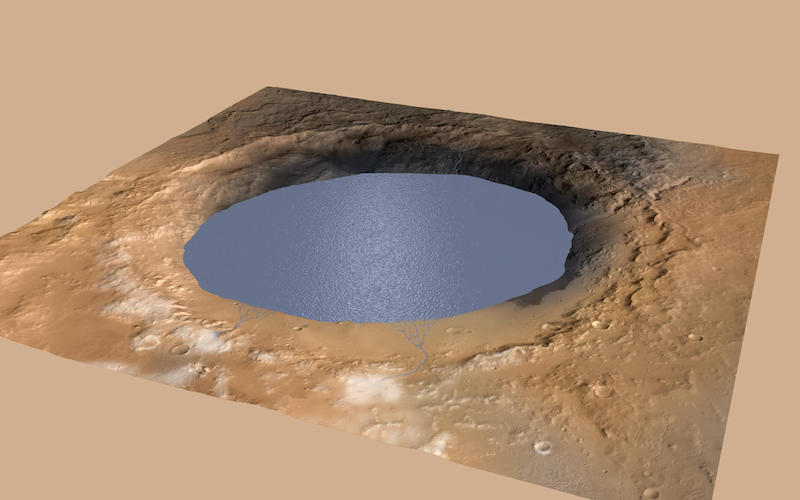 Oblique view of a round crater mostly filled with blue water.