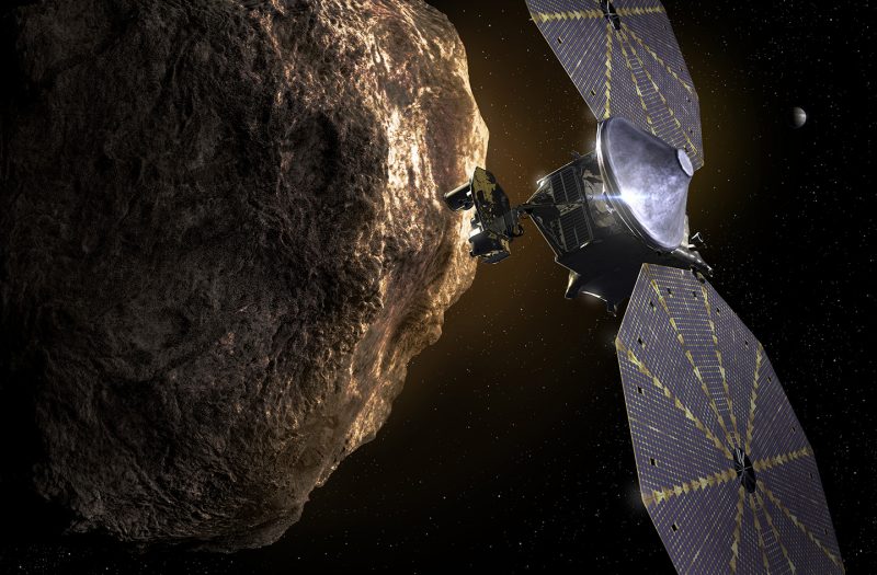 Lucy spacecraft with two large solar panels in front of large rocky object.