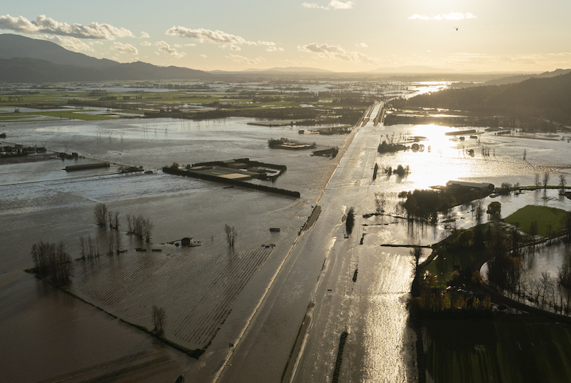 Atmospheric river: Sunlight reflecting in floodwater covering a highway and surrounding land.