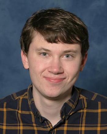 Smiling young man in black and yellow plaid shirt.