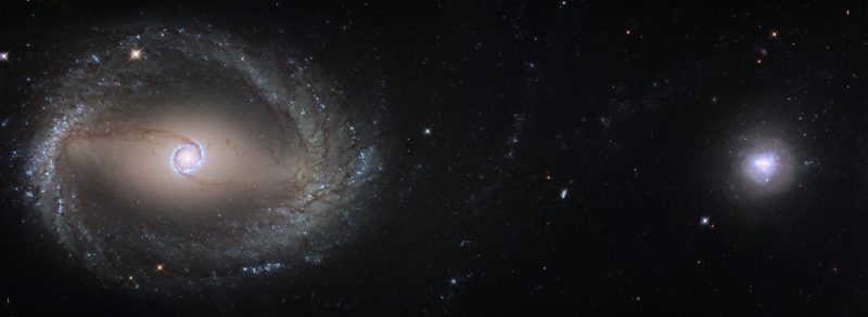 Spiral galaxy with tighter spiral at center on left, more circular blob-shaped galaxy to right, in Horologium the Pendulum Clock.