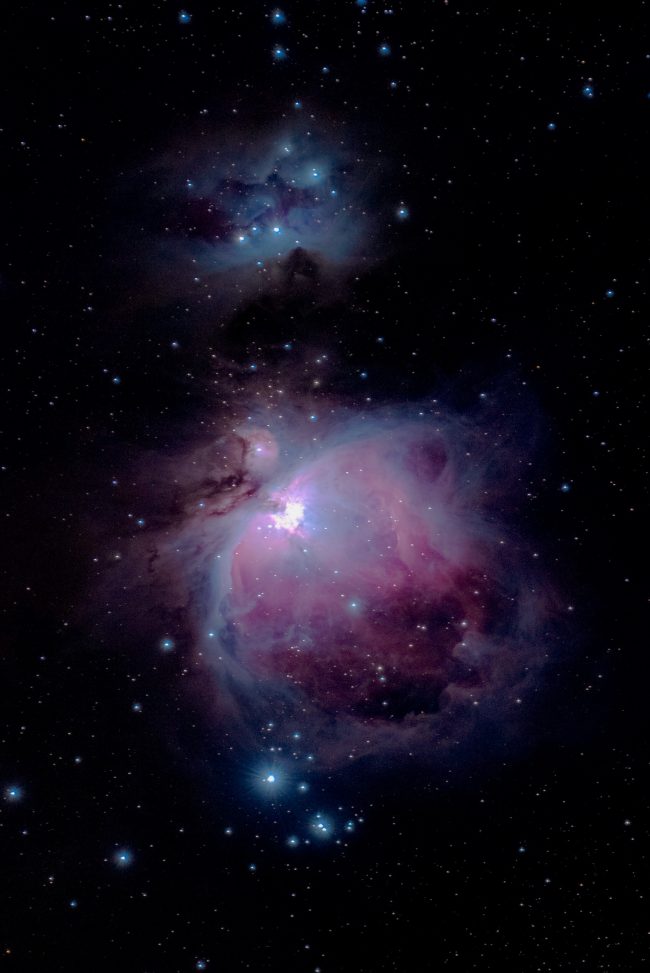 Bluish nebula at top, larger pinkish semicircular-shaped nebula at bottom, in scattered star field.