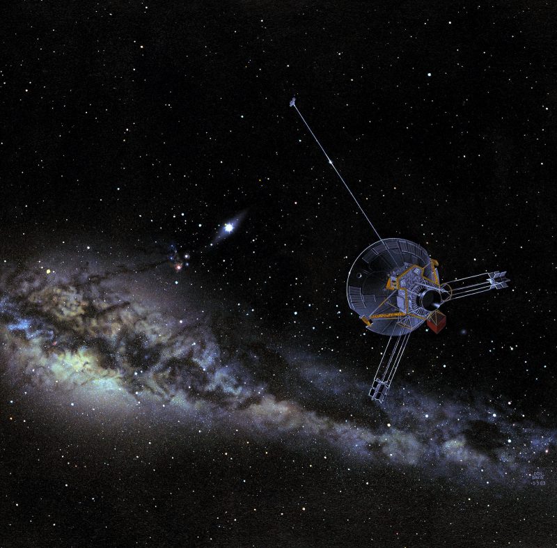 A spacecraft with a round shape, two legs and a long antenna, moves aways from a big amount of stars and a cloudy ring.
