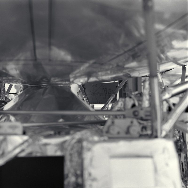 Pioneer: Structure of spacecraft in foreground out of focus, plaque in focus in background.