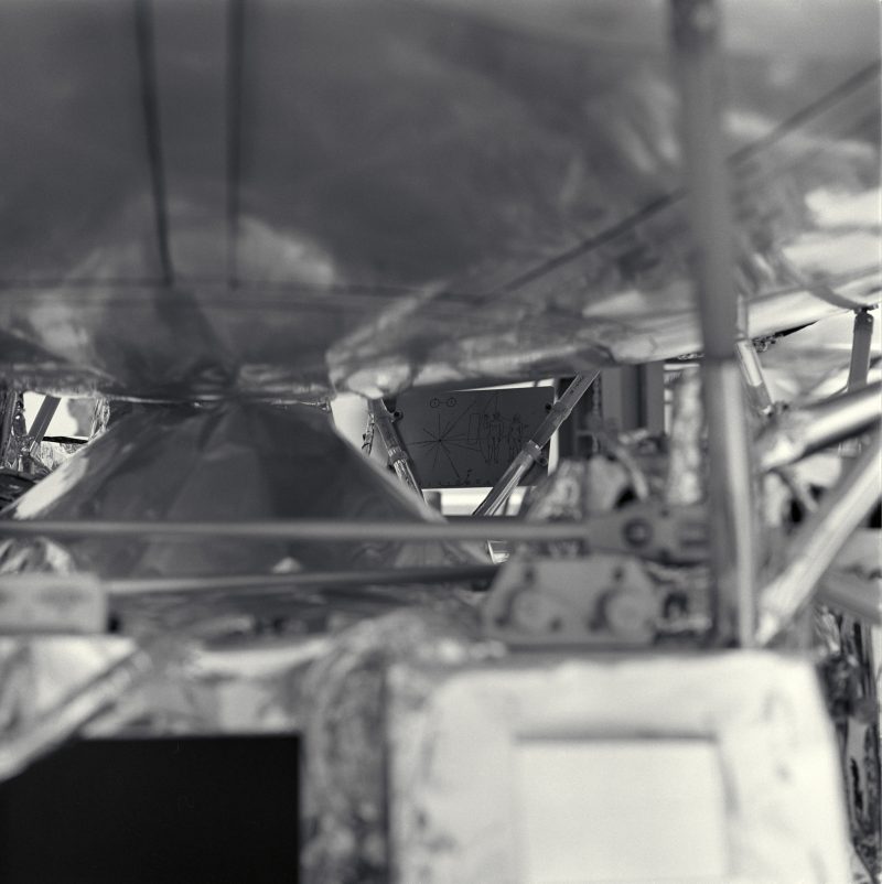 50th anniversary: Structure of spacecraft in foreground out of focus, plaque in focus in background.