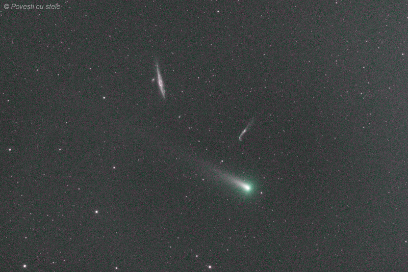 Green fuzzy comet with long tail near two elongated smudges in a starfield.