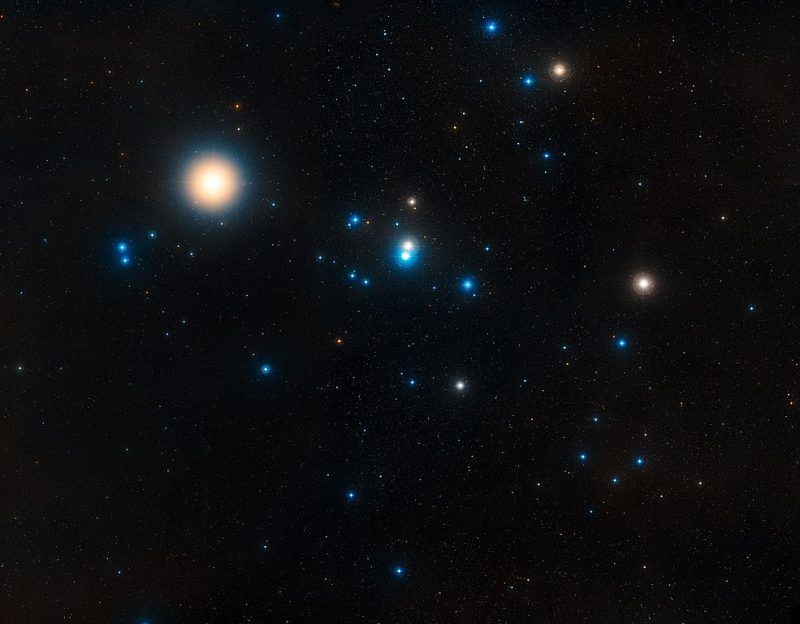 Group of bright glowing stars with a tight yellow and blue pair at center.