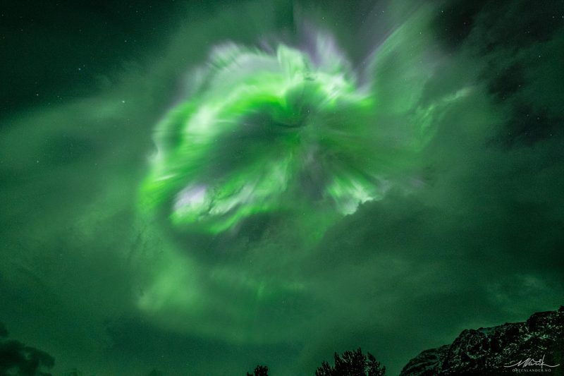 Billowing clouds of green light apparently coming right at the viewer from above in the night sky.