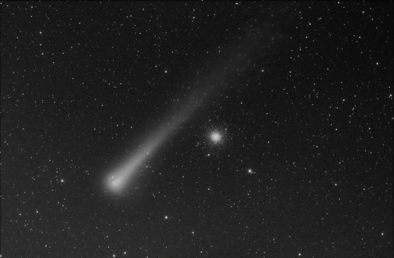 Black and white capture of a dark sky. Comet Leonard and globular star cluster.
