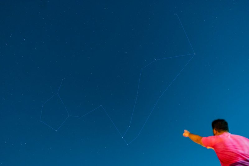 Man points to sky where Cetus is outlined in stars.