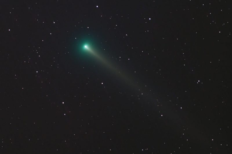 Dark sky, Comet Leonard is in the middle leaving a tail of green color.