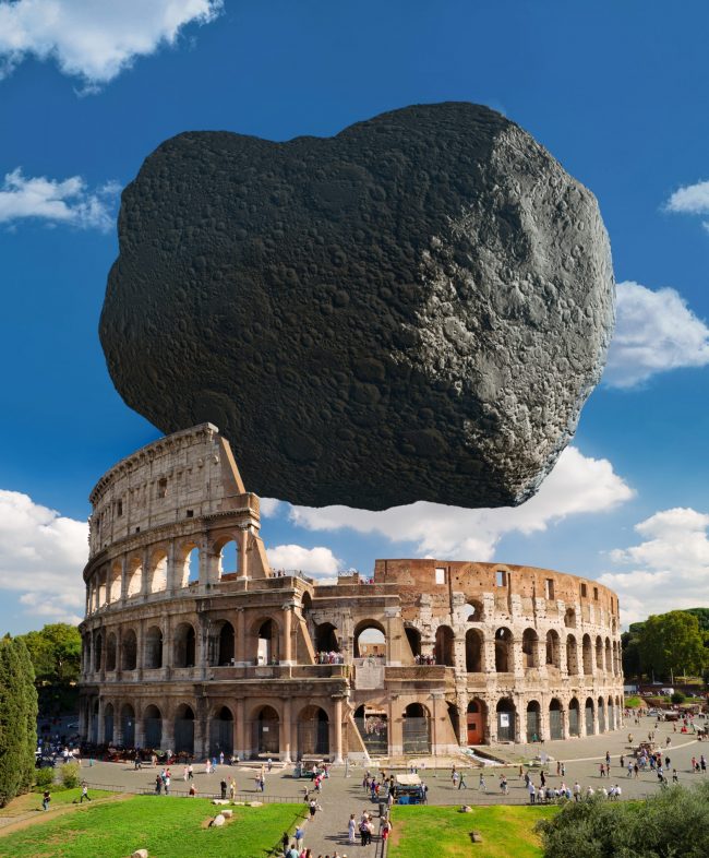 Huge, irregular rock hovering over Roman Colosseum, a large, ruined stone stadium.