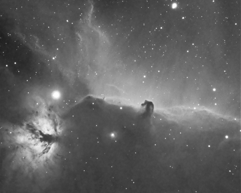 Black and white image of the cloudy dust with a flame shape at left and horsehead at center.