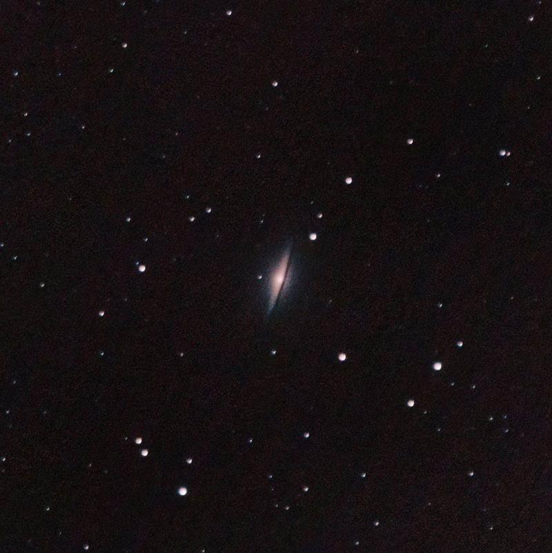 An edge-on spiral galaxy with a dust lane on its rim.