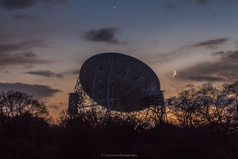 Large radio dish at sunset with the moon and Venus.