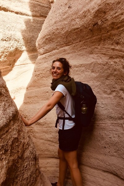Girl hiking through rock, wearing a backpack.