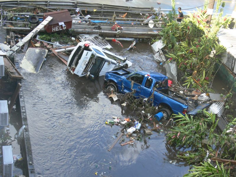 Two vehicles partially submerged in water and surrounded by debris.