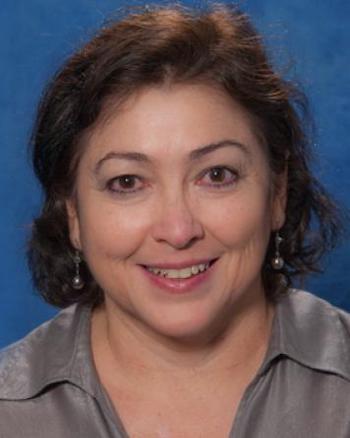 Headshot of smiling woman with dark blue background.