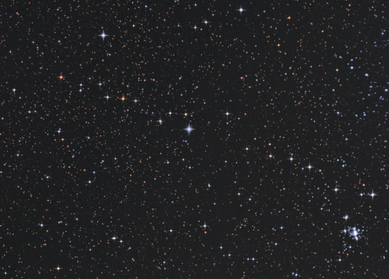 Black background with stars in a trail across center to cluster lower right.