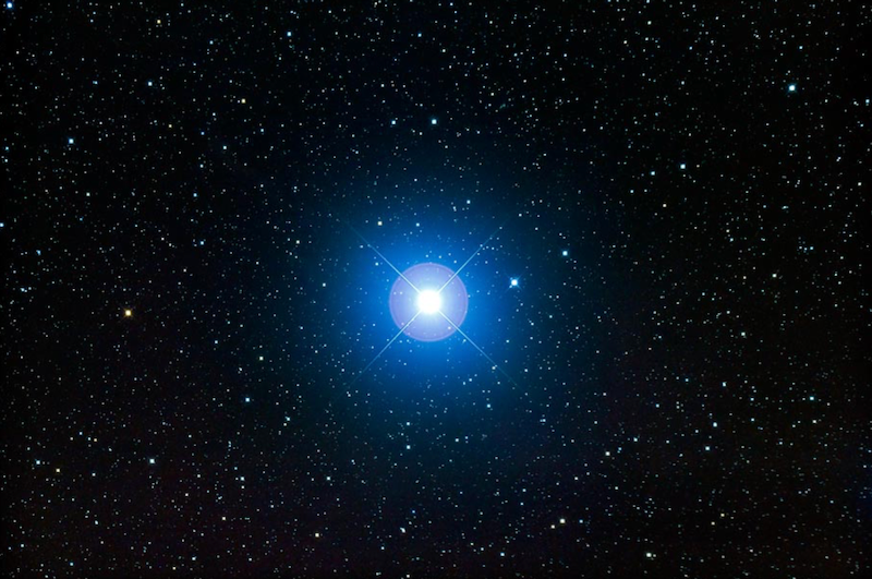 A large, bright, blue-white star in a field of many stars.