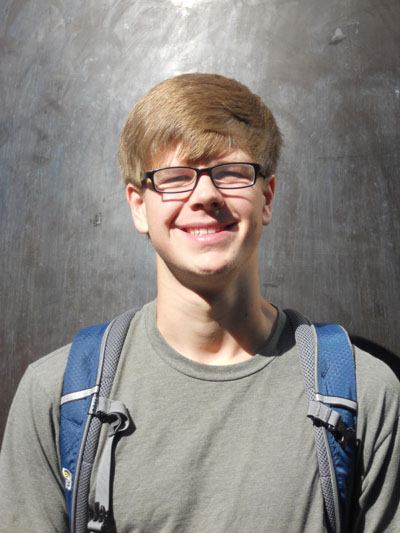 Young man with glasses and longish hair, wearing a backpack.