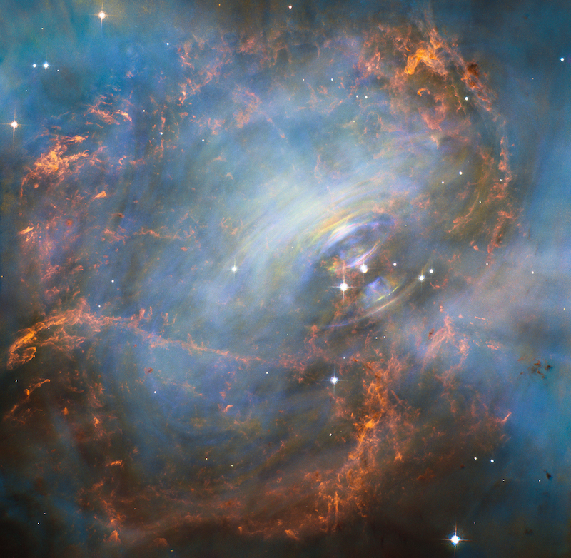 Red and blue nebulous features with bluish-white rings around a very bright star in the middle.
