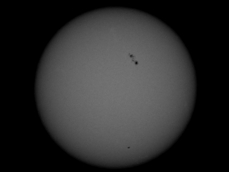 Round sun, in gray, with black irregular spots on it.